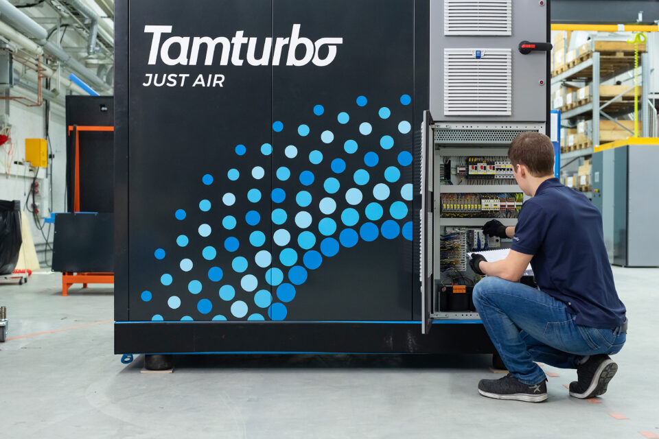 Technician servicing a Tamturbo oil‑free compressor in a production facility, showcasing energy‑efficient, maintenance‑friendly compressed air technology for industrial applications.