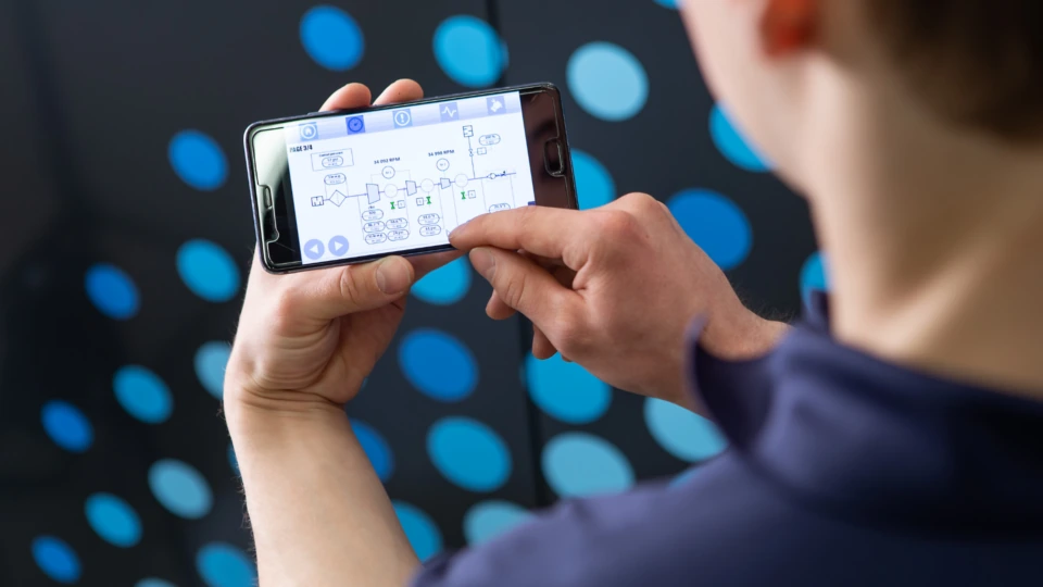 Technician using a mobile app for compressor remote monitoring on a Tamturbo turbo compressor, offering smarter control compared to screw compressor systems